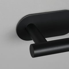 Black 304 stainless steel adhesive toilet paper holder mounted on a wall.