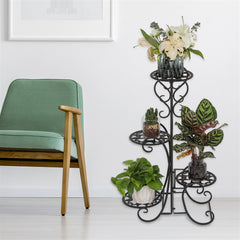 Black iron 4-tier plant stand holding four potted plants indoors.