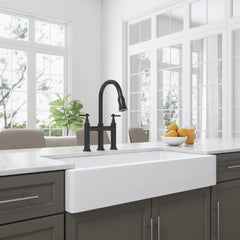 White ceramic 36-inch apron-front farmhouse sink installed in a modern kitchen with black faucet.