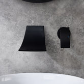 Matte black wall-mount bathroom waterfall faucet with single handle on gray surface.