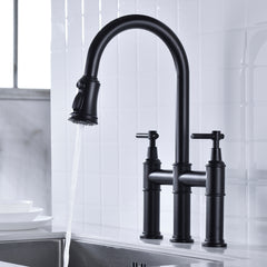 Matte black pull-down double-handle kitchen faucet with arched spout and sprayer over white sink.