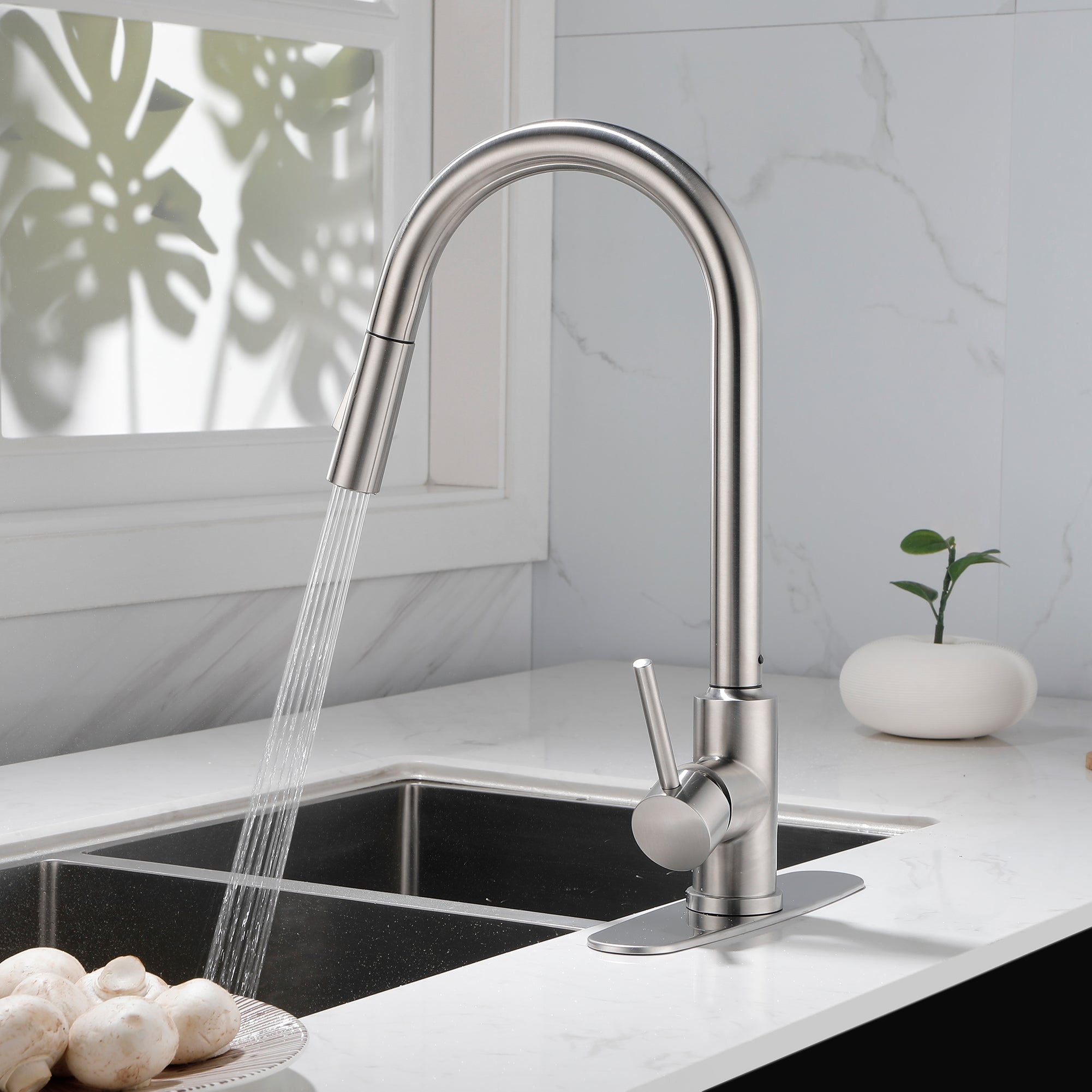 Stainless steel high arc pull-down kitchen faucet with single handle and sprayer over sink.