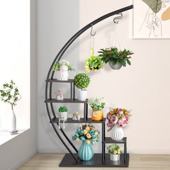 A black iron semicircle plant stand with five dark wood shelves displaying various potted plants.