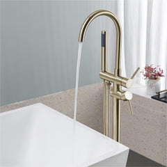 Brushed gold freestanding floor-mount bathtub faucet filling a white tub with water.