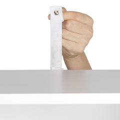 A hand holds a white fabric strap with a screw, attached to a white cabinet.