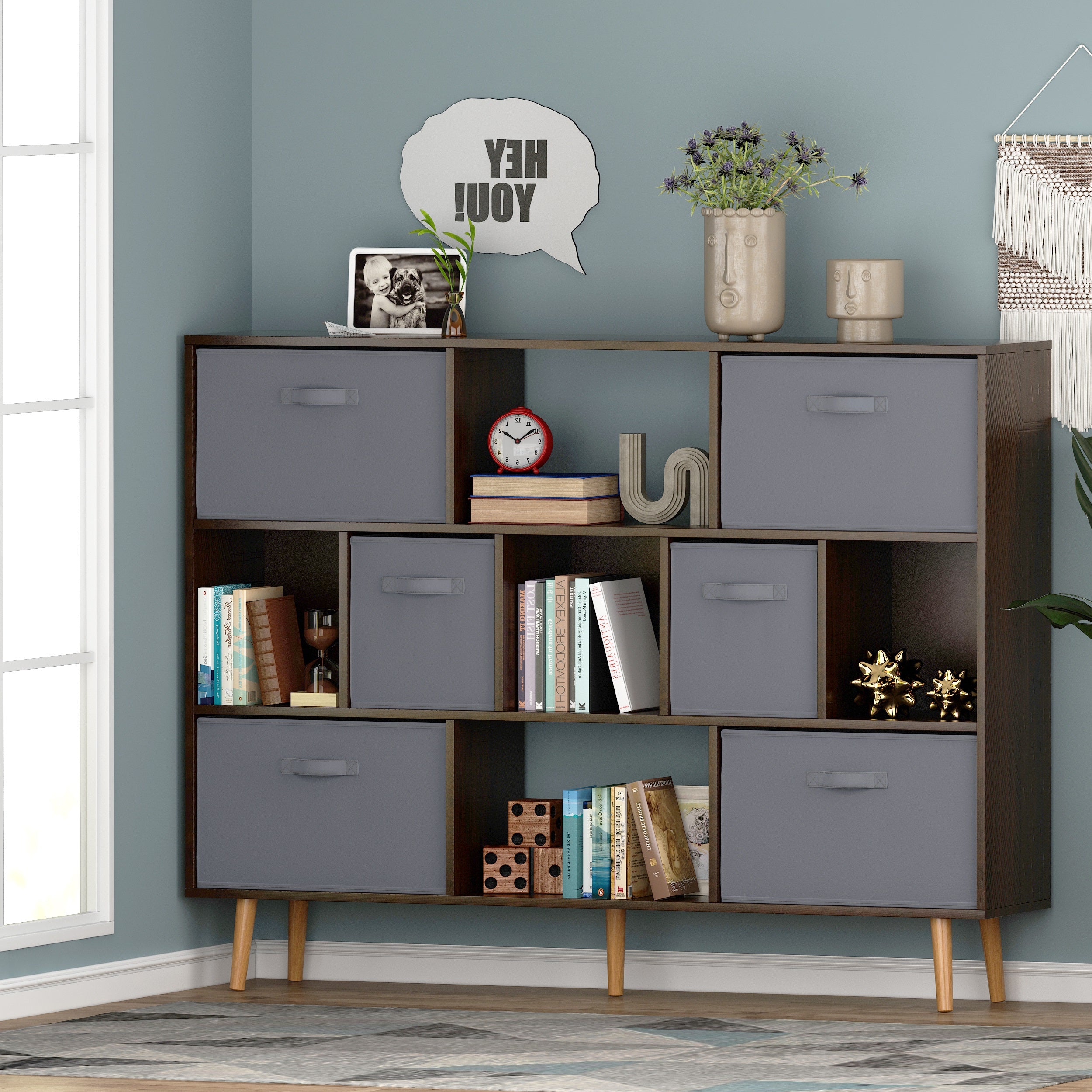 Brown wooden cube bookshelf with gray fabric drawers and open shelves on angled legs.