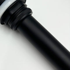 A black pop-up drain with a white gasket and ribbed nut, angled on a white background.
