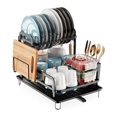 A black 2-tier carbon steel dish drying rack with drainboard, holding plates, cups, utensils, and a wooden cutting board.