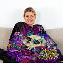 A woman wrapped in a 50x60-inch flannel throw blanket featuring a purple mushroom skull print.