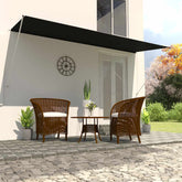 Anthracite steel retractable awning extended over a patio with wicker chairs and plants.