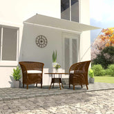 Cream retractable awning extended over wicker chairs and table on a patio.