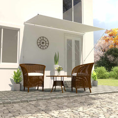 Cream retractable awning extended over wicker chairs and table on a patio.