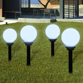 Four white glossy LED solar pathway lights with 5.9-inch balls on black stakes in a grassy yard.
