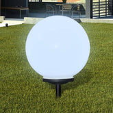 White 15.7-inch LED solar pathway lamp with glowing ball and ground spike on grass.