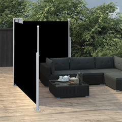 Black retractable double-side patio awning extended on a wooden deck beside a gray L-shaped sofa.
