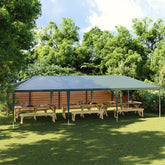 Green 13.1'x29.5' party tent with UV water-resistant PE canopy over wooden picnic tables in a backyard.