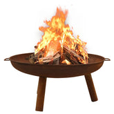 Brown rustic steel fire pit with burning logs in a round bowl on four legs.