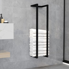 Black iron towel rack with four rungs holding stacked white towels on a gray bathroom wall.