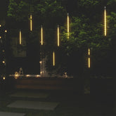 Eight warm white LED meteor rain lights hanging from a tree, creating a cascading glow.
