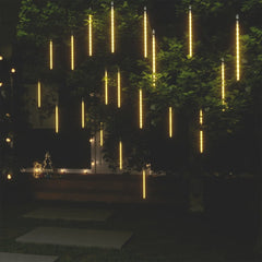 20 warm white LED meteor rain lights hanging from a tree at night, creating a falling star effect.