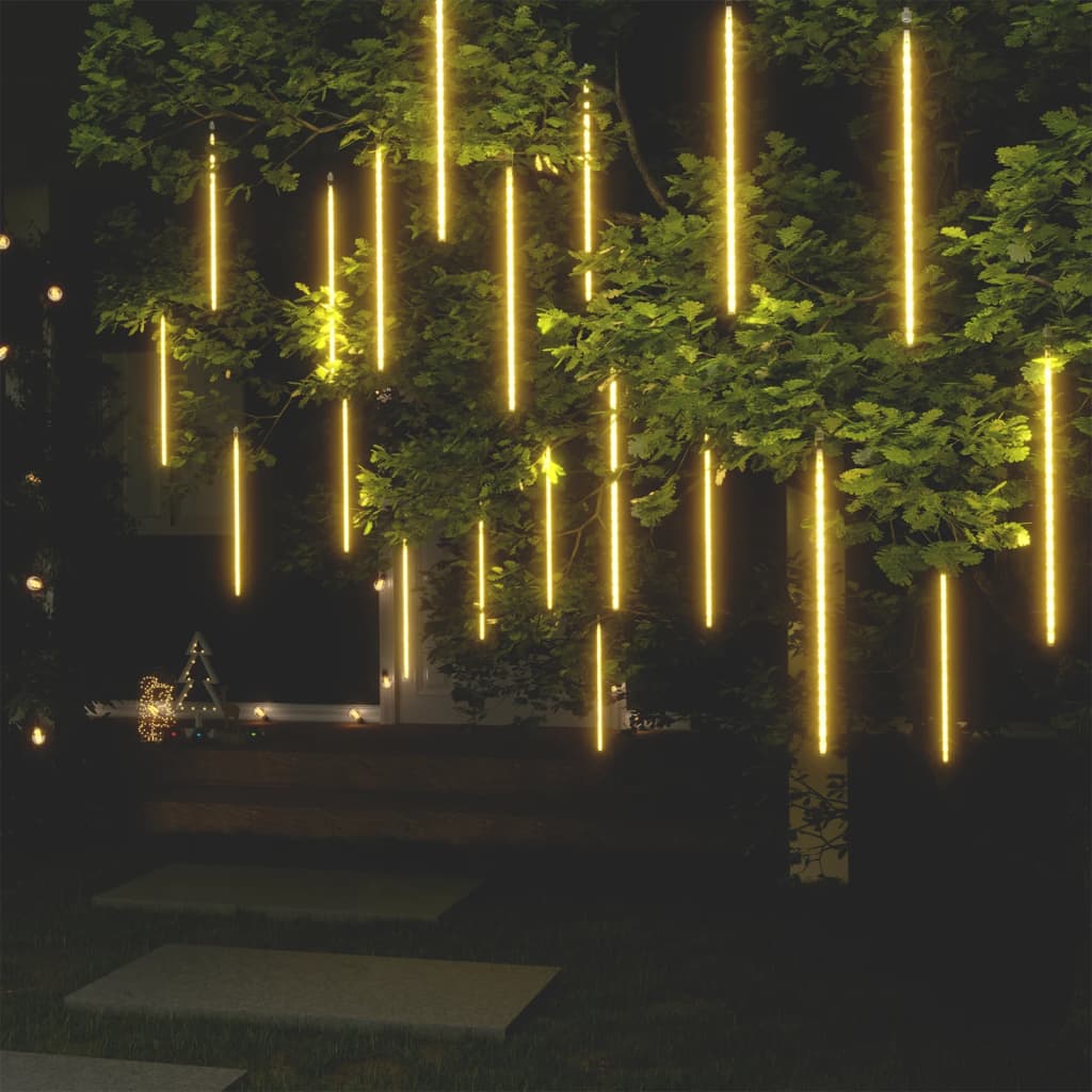 20 pieces of 2ft warm white meteor rain lights with 720 LEDs cascading from a tree at night.