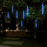 Eight blue LED tubes hanging from tree branches creating a meteor rain light effect at night