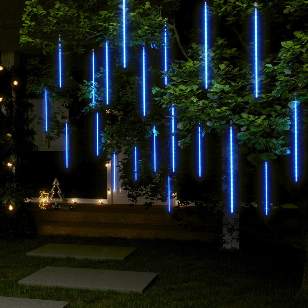 Blue LED meteor shower string lights hanging from tree branches outdoors at night.