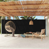 Black retractable side awning extended on a terrace with hanging egg chair and plants.