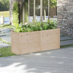 A rectangular solid pine wood garden planter filled with green plants, measuring 59.1x19.7x27.6 inches, placed on a patio near a stone wall.