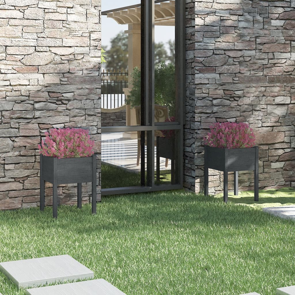 Two gray solid pine wood garden planters with pink flowers flank a modern stone house exterior.