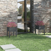 Two gray solid pine wood garden planters with pink flowers flank a modern stone house exterior.