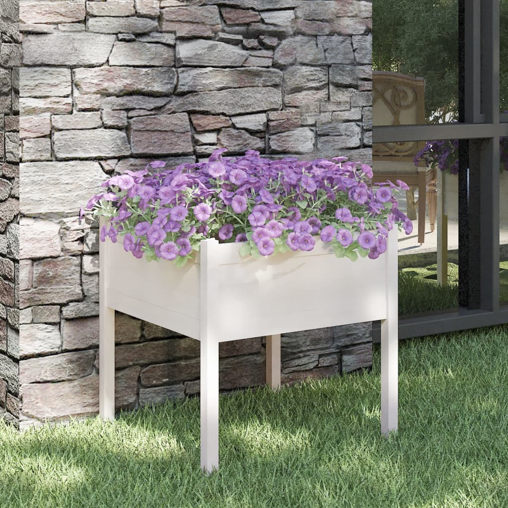 White solid pine cube garden planter with purple flowers against a stone wall.