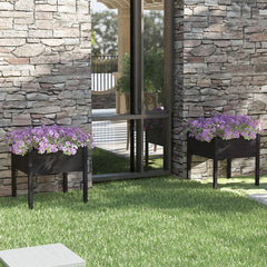 Two black 27.6-inch square pine wood garden planters with purple flowers, placed on grass against a stone wall.