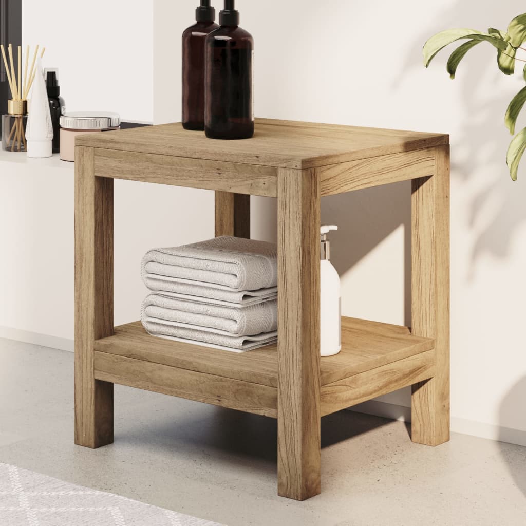 Solid teak wood bathroom side table with lower shelf holding folded towels and a lotion bottle.