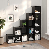 Black 15-cube storage organizer with modular cubes arranged in a staircase shape, holding books, plants, and decor.