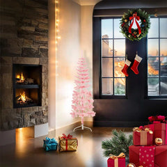 A 4 ft slim pink artificial half Christmas tree stands against a wall in a cozy room with holiday decorations.