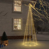 A 10 ft outdoor Christmas tree with 310 warm white LEDs and ground spike, glowing against a snowy house at night.