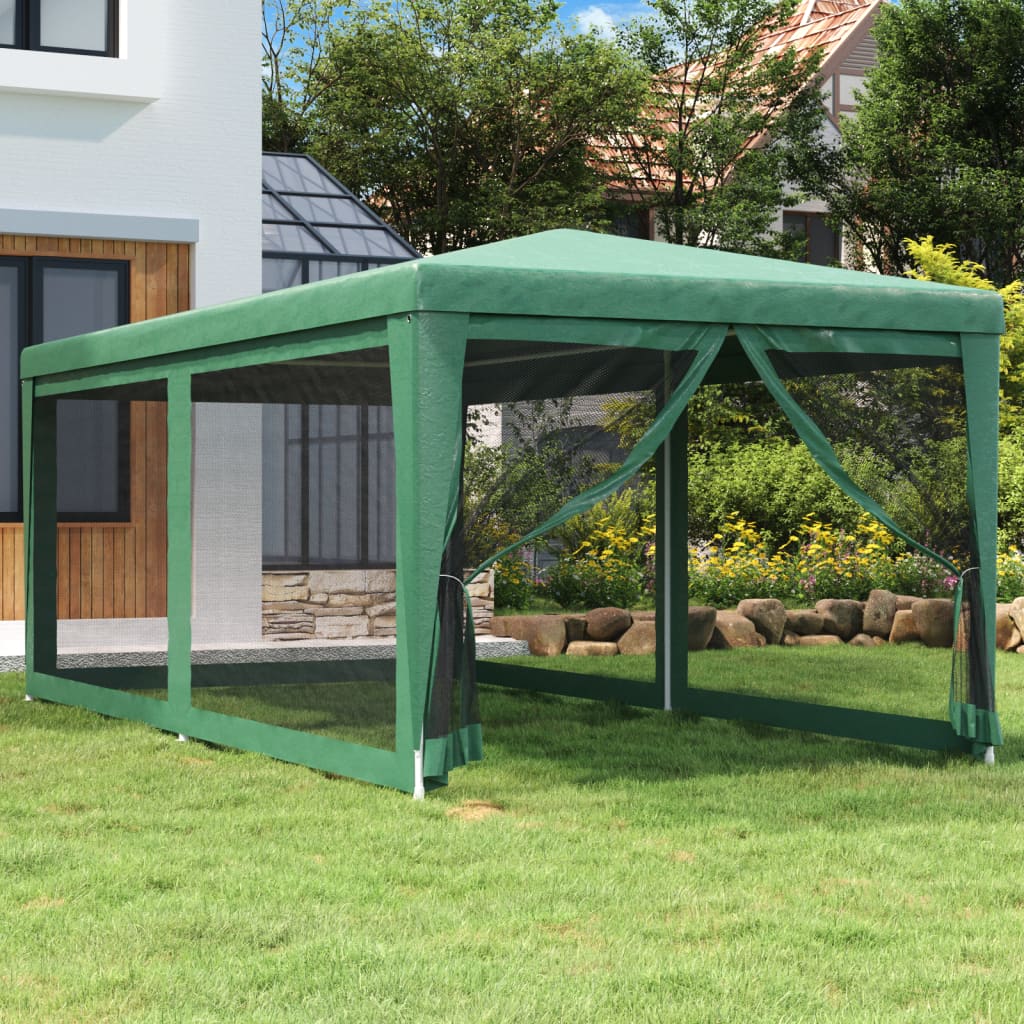 Green HDPE party tent with mesh sidewalls set up on a lawn near a house.