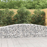 Three arched galvanized iron gabion baskets filled with gray stones, forming a curved garden wall.