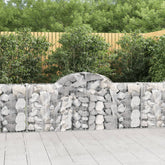 Four galvanized iron arched gabion baskets for garden walls, filled with rocks or gravel.