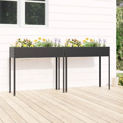 Two anthracite galvanized steel garden planters with flowers, on a wooden deck against a white house.