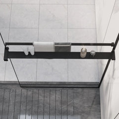 Black aluminum shower shelf mounted on glass wall, holding towels, bottles, and soap.