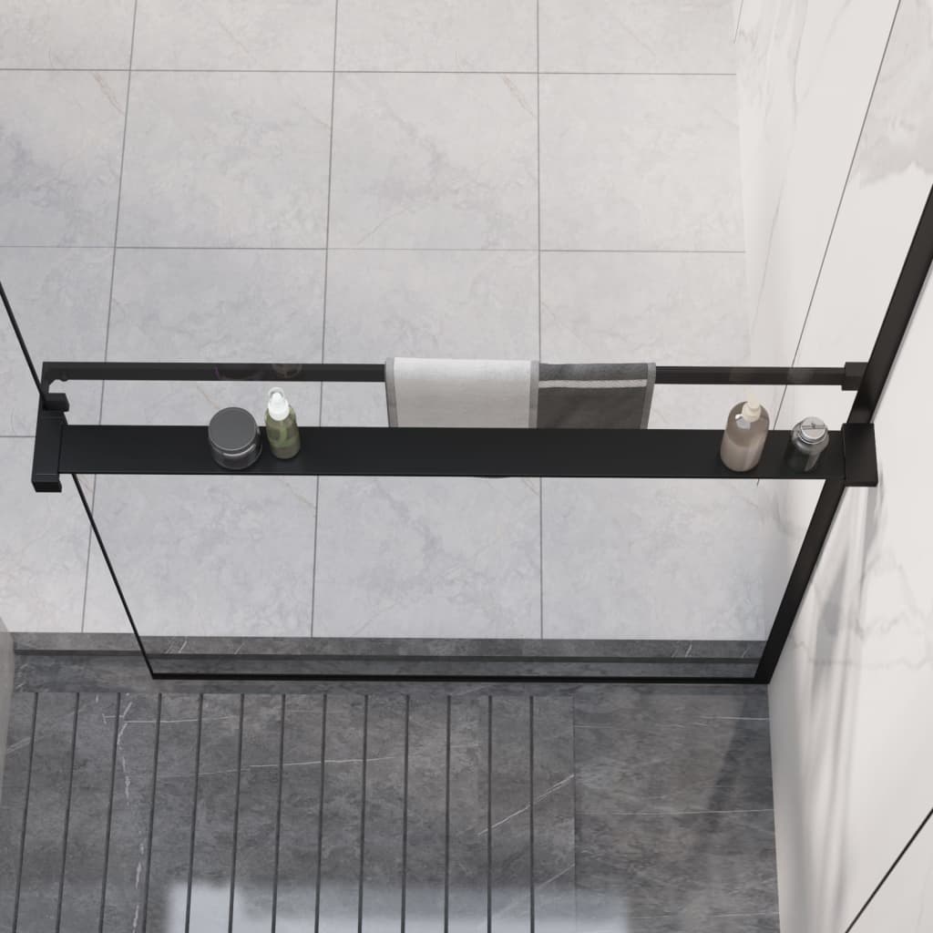 Black aluminum shower shelf with towel bar mounted on glass wall in tiled walk-in shower.