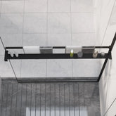 Black aluminum shower shelf mounted on walk-in shower wall with glass panels, holding shampoo bottles.