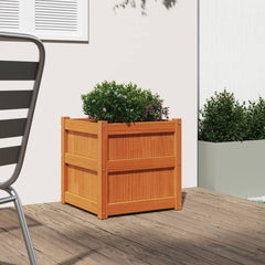 Square wax brown solid pine wood garden planter with boxwood plant on patio.