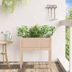 Wooden pine garden planter with legs, filled with green plants on a balcony.