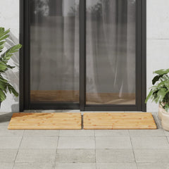 Two light brown bamboo bath mats are placed on a tiled patio in front of glass doors.