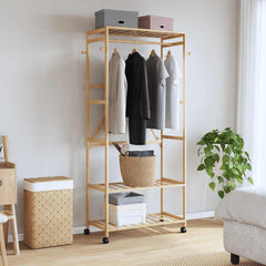 Natural bamboo clothes rack with shelves, hooks, and wheels in a bedroom setting.