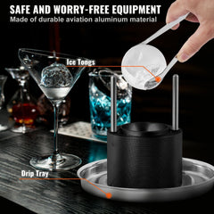 A black aluminum ice ball press kit with tongs and a drip tray on a bar counter.