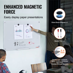 A 36x24 inch frameless magnetic glass whiteboard with magnets, markers, and a hand pointing to attached papers.